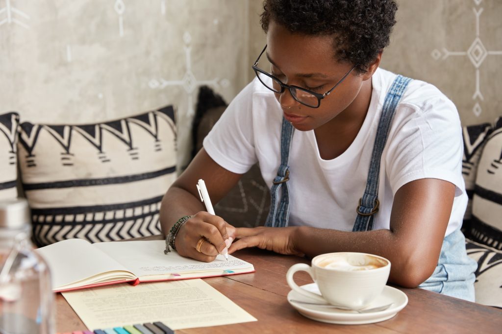 Photo of self employed black professional young entrepreneur writes good ideas to develop her busine